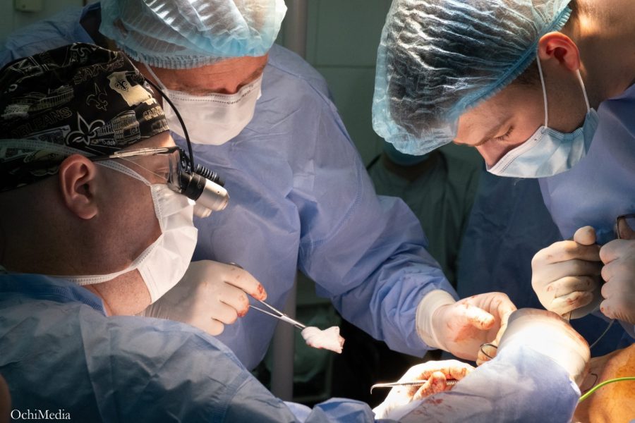 three surgeons operating on a patient